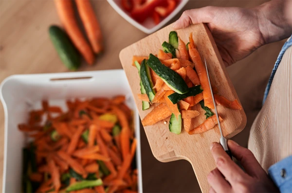 Scraping vegetable slices into a bin
