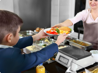 School caterer handing healthy school meal to pupil